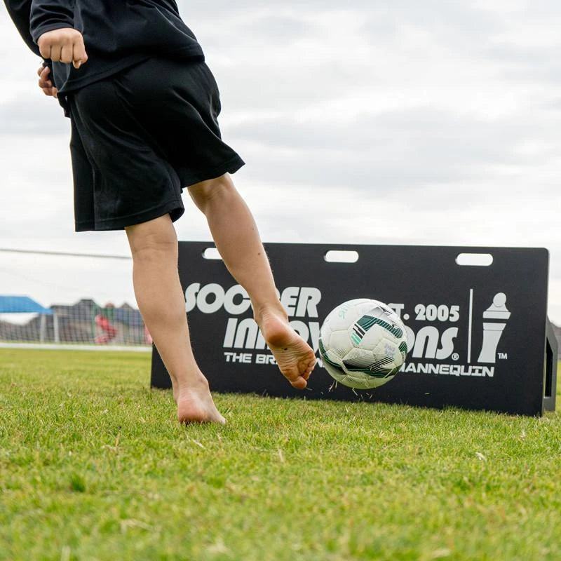 Soccer rebounder board standing upright on field showing sturdy frame and netting for ball return